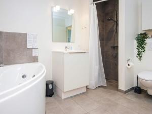 a bathroom with a tub and a sink and a toilet at 8 person holiday home in Ringkøbing in Ringkøbing +178 photos