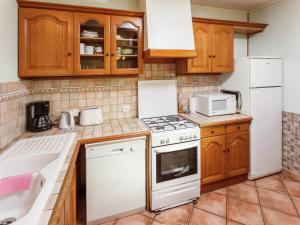 eine Küche mit weißen Geräten und Holzschränken in der Unterkunft Rustic Retreat for Families in Villefranche-du-Périgord