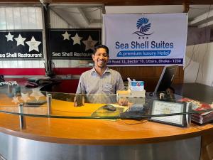 KāmarpāraSea Shell Suites的坐在电脑柜台上的人