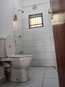 a white bathroom with a toilet and a window at Ranks Comfy Homes in Mombasa