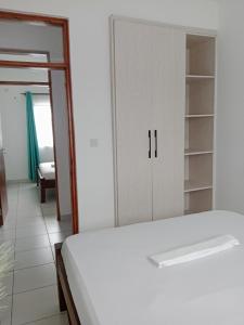a bedroom with a white bed and a closet at Ranks Comfy Homes in Mombasa