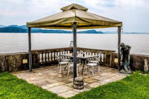 La Villa di Elena في فيربانيا: طاولة وكراسي تحت مظلة بجانب الماء