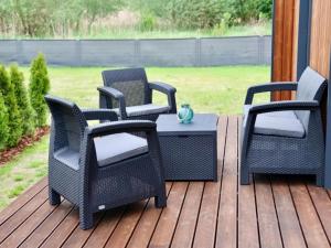 three wicker chairs and a table on a deck at Comfortable house by the beach in Stepnica in Stepnica