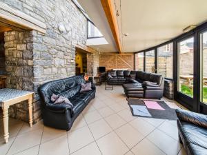 a living room with leather furniture and a stone wall at Han-sur-Lesse cottage in Han-sur-Lesse