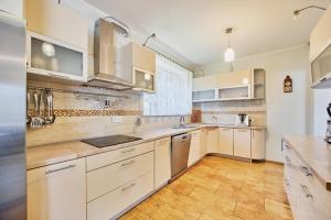 Comfortable holiday home, Swinoujscie في سفينويتشي: مطبخ كبير مع دواليب بيضاء وارضية خشبية