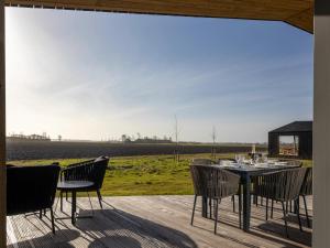 un patio con mesa, sillas y un campo en Beautiful holiday home with terrace, en Wissenkerke