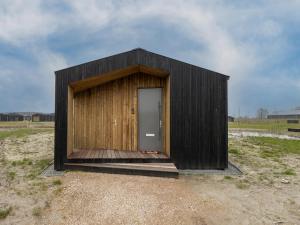 a small wooden building with a door in a field at Lovely holiday home in Wissenkerke with garden in Wissenkerke