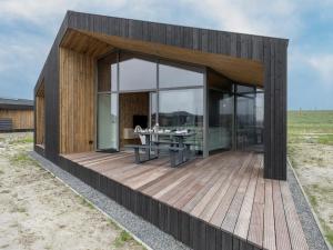 a house with a wooden deck with a table at Lovely holiday home in Wissenkerke with garden in Wissenkerke