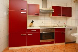 SewekowにあるFeriensiedlung Am Grundlossee in Sewekowのキッチン(赤いキャビネット、シンク付)