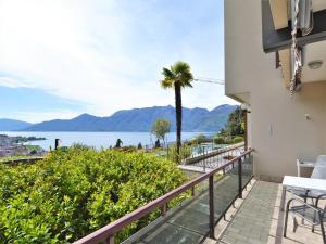 a balcony with a view of the water and a palm tree at Belvilla by OYO VC02 7 - Villa Castiglioni in Luino
