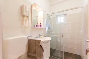 a white bathroom with a shower and a sink at Rooms Vilena in Medulin