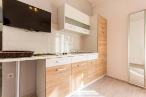 a kitchen with white cabinets and a flat screen tv at Rooms Vilena in Medulin