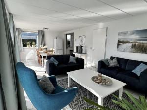 a living room with blue chairs and a table at comfortable bungalow for 6 people, in Sint Maartenszee