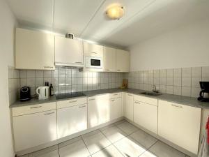 a white kitchen with white cabinets and a microwave at comfortable bungalow for 6 people, in Sint Maartenszee