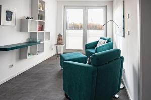 ペーネミュンデにあるFerienhaus am Yachthafen in Peenemuendeのリビングルーム(緑の椅子2脚、窓付)