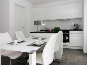 ペーネミュンデにあるFerienhaus am Yachthafen in Peenemuendeの白いキッチン(テーブル、白い椅子付) +62枚の写真