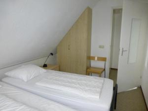 a bedroom with a white bed and a chair at bungalow for 6 people, near the beach in Sint Maartenszee