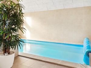 a pool with a palm tree in a building at 14 person holiday home in Væggerløse in Marielyst