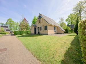a house with a grassy yard next to a driveway at Spacious bungalow near the Frisian Lakes in Sondel