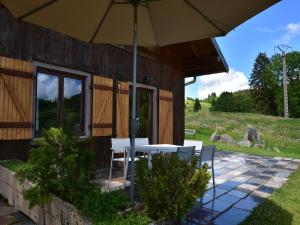 a table and chairs under an umbrella on a patio at Chalet in Saulxures near Ski Resorts in Saulxures-sur-Moselotte +32 photos