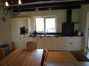 a kitchen with white cabinets and a wooden table at Holiday Home Schoonoord near Kibbelkoele in Kibbelveen