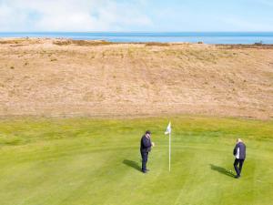 two men standing on a golf course with a flag at Læsø Seaside Holiday Homes in Læsø +36 photos