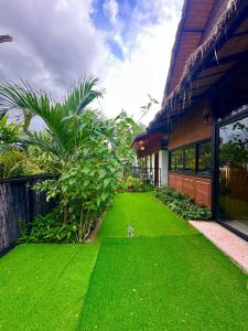 a yard with green grass next to a building at Studio Ground Floor Room by Densy Angkor in Siem Reap