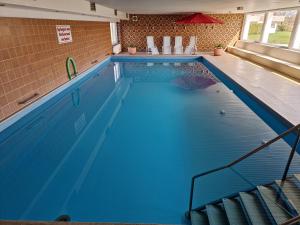 a swimming pool with blue water in a building at Tief 10 mit beheiztem Pool - Meerengel 1001 in Wangerland +51 photos