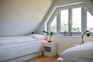 een slaapkamer met twee bedden en twee ramen bij Haus Dock 10 in Westerland