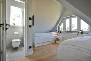 een witte slaapkamer met 2 bedden en ramen bij Haus Dock 10 in Westerland +25 foto's