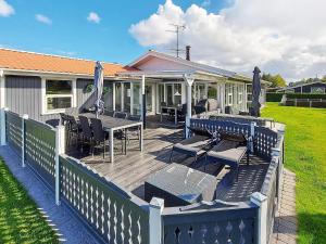 a wooden deck with chairs and tables on a house at 12 person holiday home in Hadsund-By Traum in Nørre Hurup