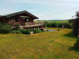 TennevilleにあるQuiet chalet with panoramic view and fenced gardenの庭にデッキ付きのログキャビン