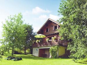 a wooden house with a balcony with an umbrella at Chalet in Hommert near Sarrebourg in Hommert