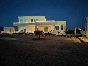 a white house with a tree in front of it at Dimora Cala Graziosa in Favignana