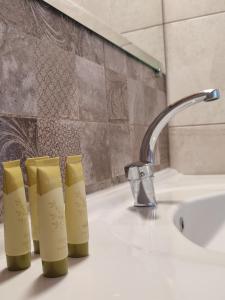 a bathroom sink with three shampoo bottles on it at VILLA IATROU in Potos +42 photos