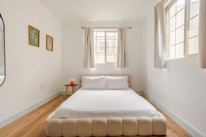 a white bedroom with a large bed with white sheets at Cozy Stay Near Fishtown - Close to Subway & Center City! in Philadelphia