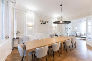a dining room with a large wooden table and white chairs at Maison Lafayette - COLODGE in Mulhouse