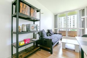 a living room with a couch and a shelf at Le Petit Auber & son balcon, à 2 pas de Paris in Aubervilliers