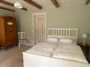a bedroom with a white bed and a chair at Torsholma Skolhus in Hallaryd