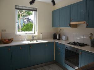 a kitchen with blue cabinets and a window at Holiday Home in Noordwijk near the Beach in Noordwijk