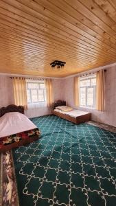a large room with two beds and a wooden ceiling at Dilovar's Homestay 