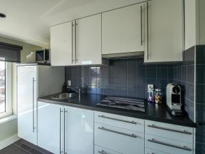 Una cocina con gabinetes blancos y una encimera negra. en Apartment in Katwijk near the Beach, en Katwijk