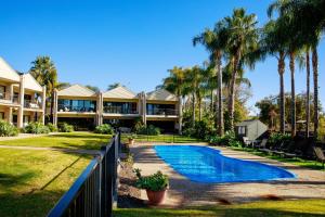 a house with a swimming pool and palm trees at Elsinor Townhouse 1 in Mulwala