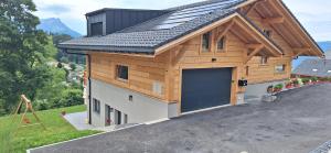 a house with a garage with a gambrel roof at Le Petit Lu in Leysin