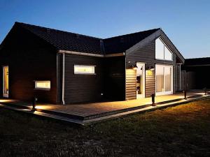 a black house with a deck in front of it at 10 person holiday home in Brovst-By Traum in Brovst
