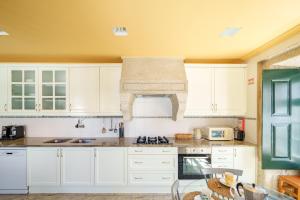 eine Küche mit weißen Schränken und einem Herd mit Backofen in der Unterkunft Feel Discovery Casa Da Capela Douro Valley in Armamar