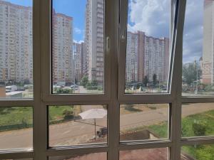 a window view of a city with tall buildings at Apartment Второй этаж, метро Позняки in Kyiv