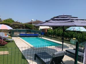 a swimming pool with chairs and umbrellas next to it at La maison d’Eloi in Montignac-Charente
