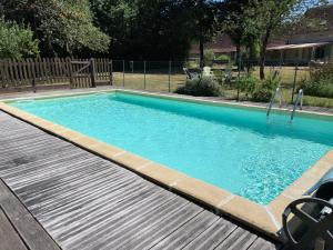 a swimming pool with blue water in a yard at La Maison de Maître, Loire Gîte in Fléré-la-Rivière
