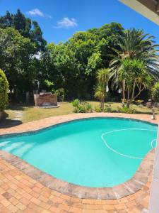 a large blue swimming pool with trees in the background at Somerset west Stay 1 in Somerset West